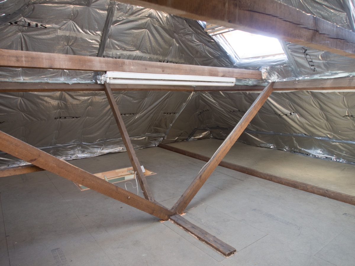 Loft conversion in progress with exposed roof beams and insulation