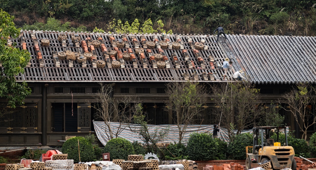 Roofers repairing tiled roof on scaffolding